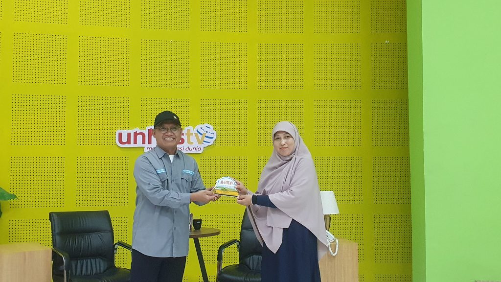 Perwakilan Guru SMAIT Al-Fityan School Gowa, Hasrianti, saat menyerahkan plakat kepada pimpinan Unhas Tv, (20/2/24).